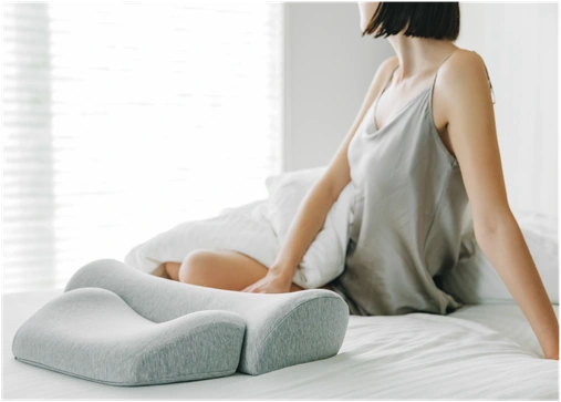ベッドに置いたダブルまくらに手を添える女性